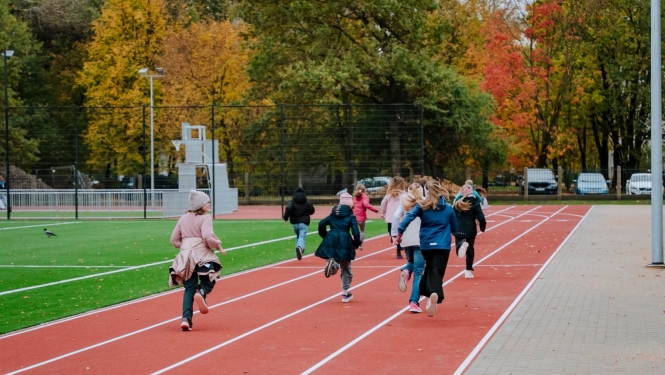 Bērni skrien pa jaunā sporta laukuma skrejceliņiem