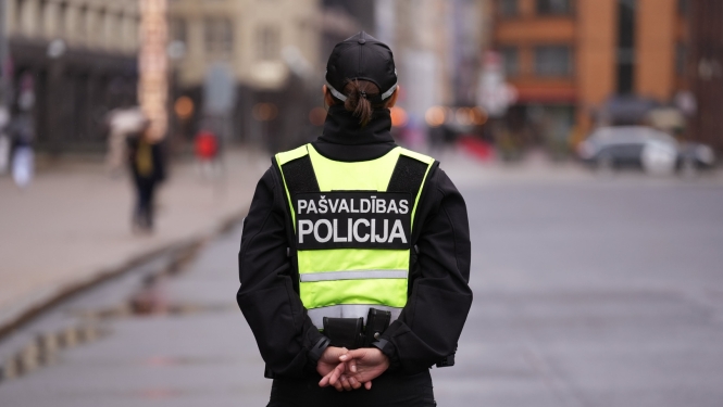 Policiste stāv ar muguru