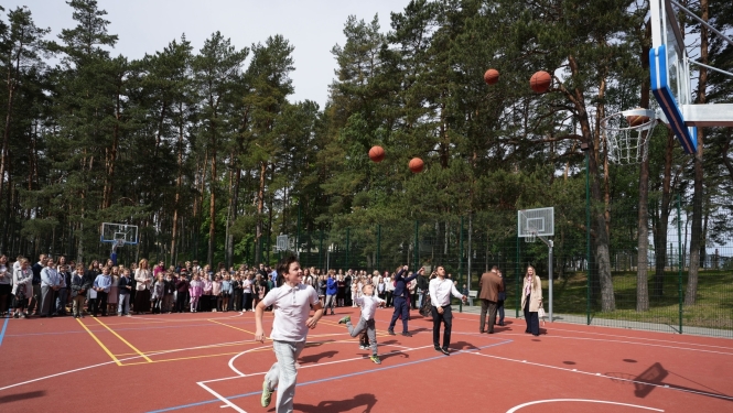 Bērni met bumbas basketbola grozā