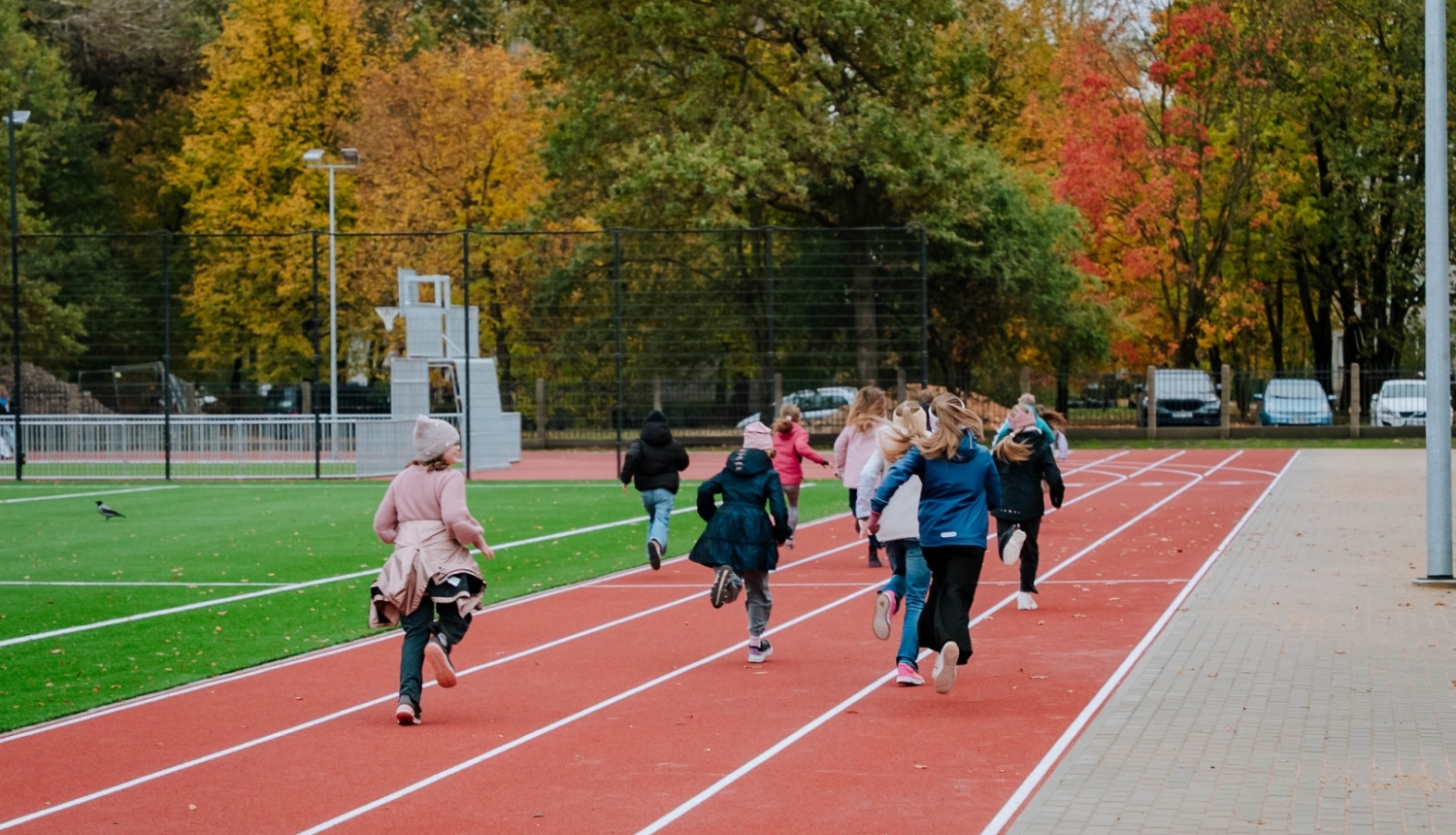 Bērni skrien pa jaunā sporta laukuma skrejceliņiem