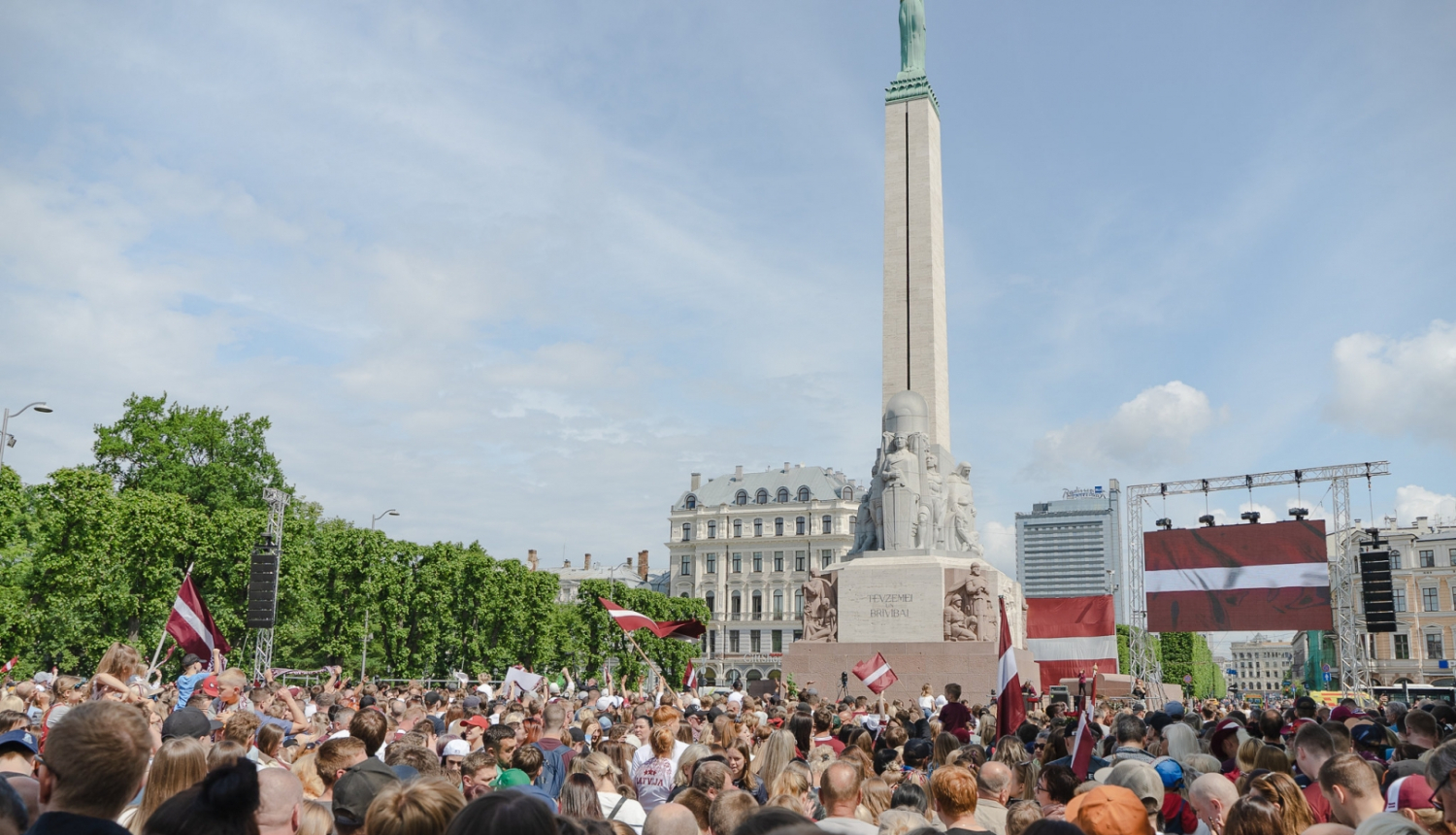 Daudz cilvēku ar karogiem rokjās pie Brīvības pieminekļa