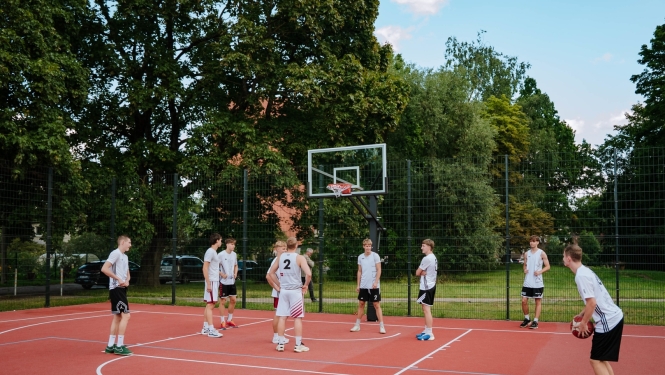 Sporta laukumā spēlē basketbolu
