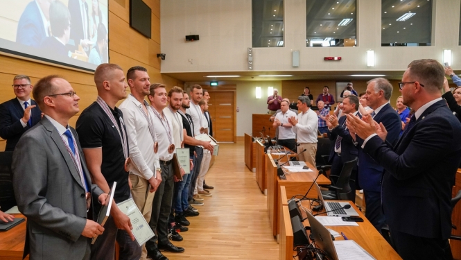 Cilvēki stāvot kājās sveic sportistus