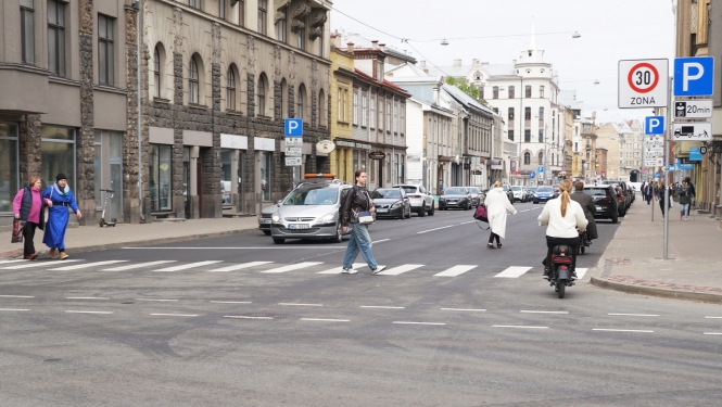 Auto brauc un cilvēki iet pa Matīsa ielu