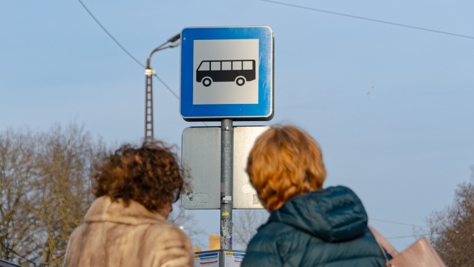 Cilvēki sabiedriskā transporta pieturā