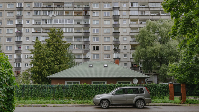 Daudzdzīvokļu mājas priekšā automašīna