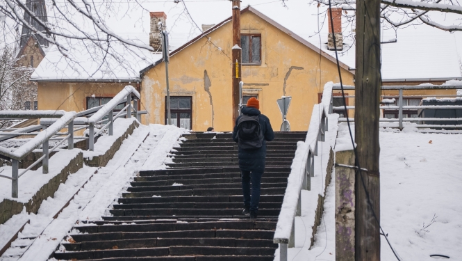 Cilvēks ziemā kāpj pa kāpnēm