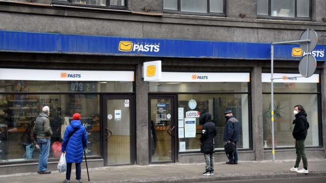 Cilvēki stāv rindā pie Latvijas pasta