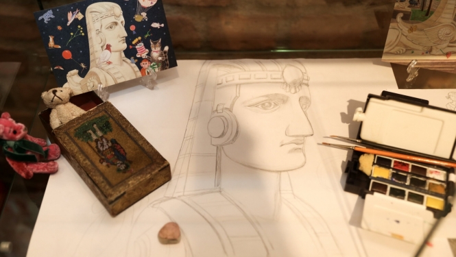 Uz galda sfinksas figūra, papīrs ars finksas zīmējumu un akvareļi krāsas