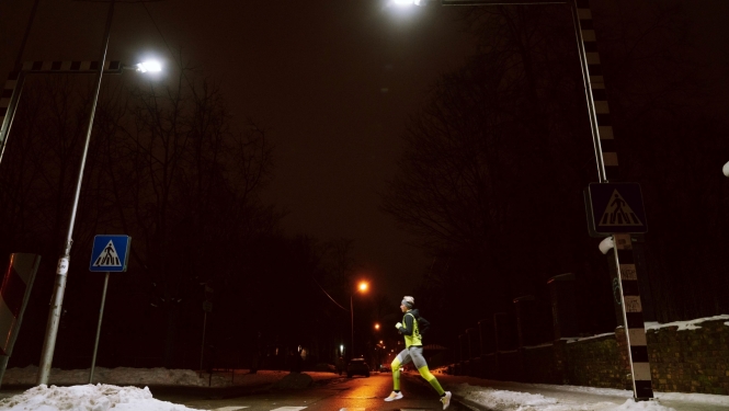 Sportists skrien pār ar LED gaismekļiem izgaismotu gajēju pāreju