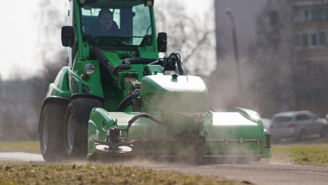 Traktors savāc smiltis no ielas