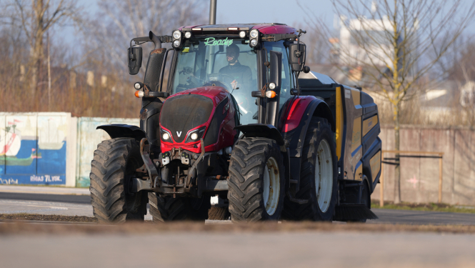Traktors savāc smiltis no ielas