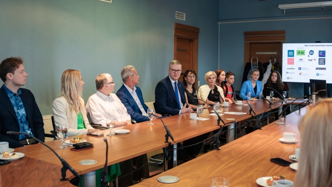 Cilvēki sēž pie galda un skatās prezentāciju