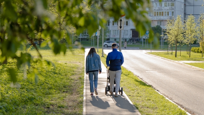 Vecāki pastaigājas ar bērnu ratiņos