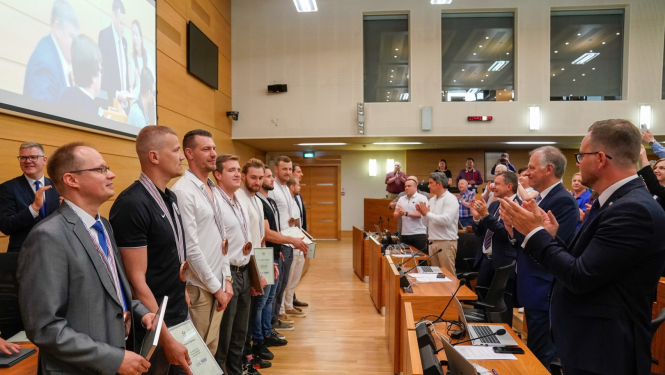 Cilvēki stāvot kājās sveic sportistus