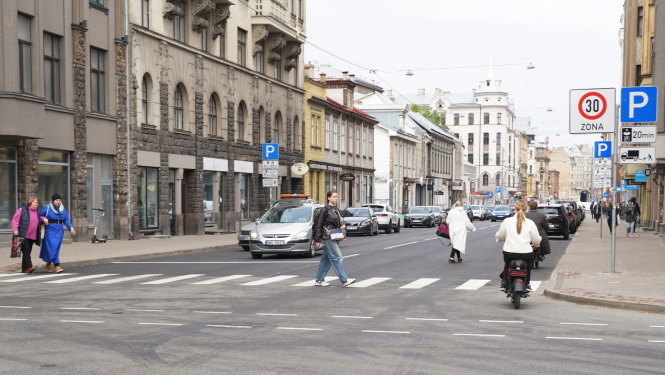 Auto brauc un cilvēki iet pa Matīsa ielu