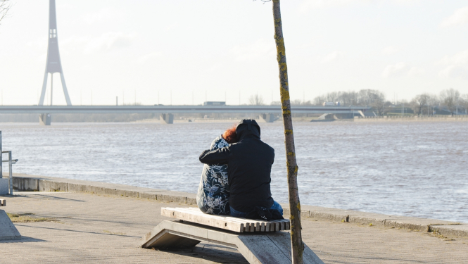 Cilvēki apķērušies sēž uz soliņa