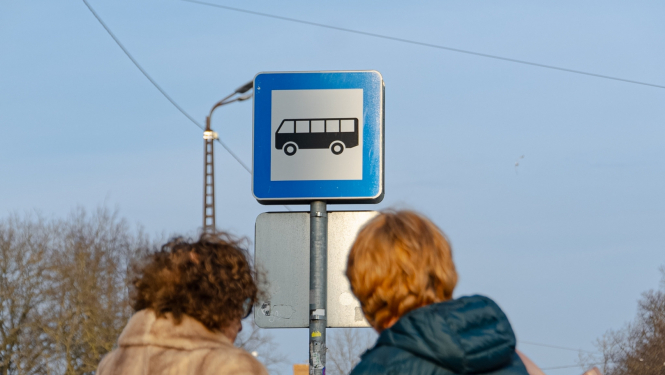 Cilvēki sabiedriskā transporta pieturā