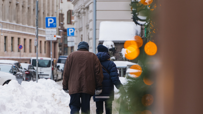 Cilvēki iet pa sniegotu ielu