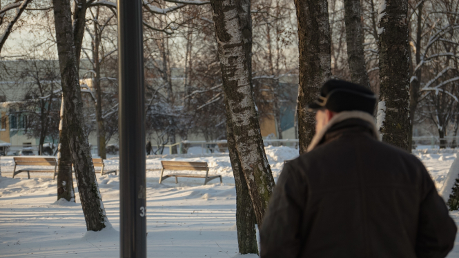 Cilvēks staigā parkā ziemā