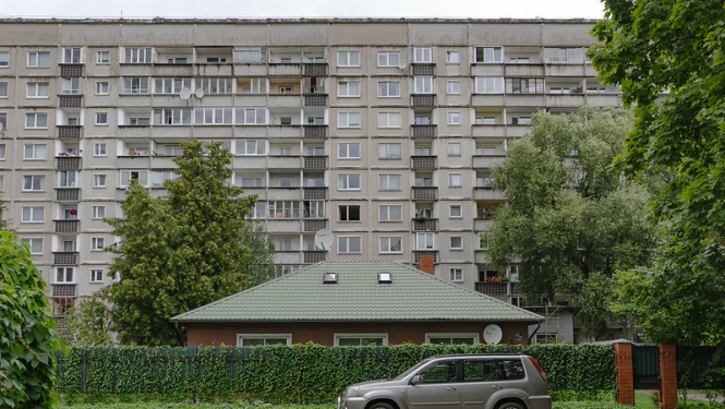 Daudzdzīvokļu mājas priekšā automašīna