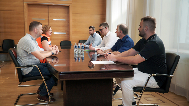 Cilvēki sēž sapulcē pie galda