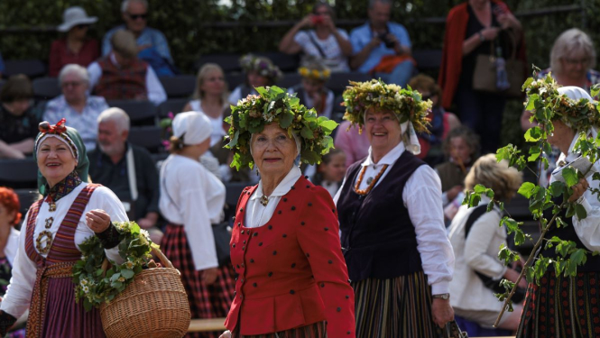 Sievietes ģērbtas tautas tērpos un ziedu vainagi galvā