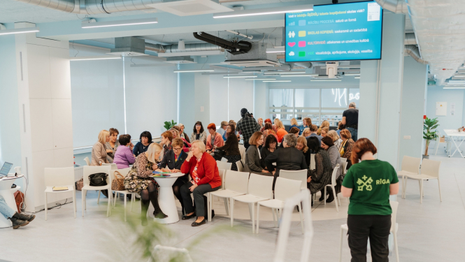 Darba grupās cilvēki sēž pie galda un rsina uzdevumus