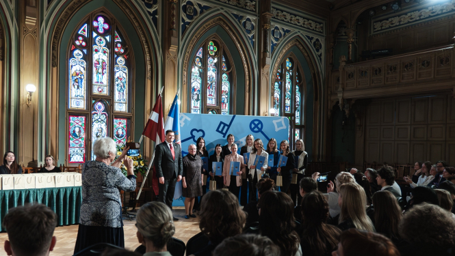 Apbalvotie skolēni fotografējas skatuves priekšā