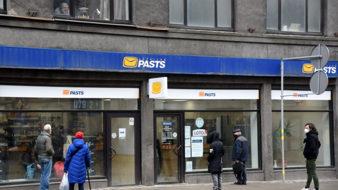 Cilvēki stāv rindā pie Latvijas pasta