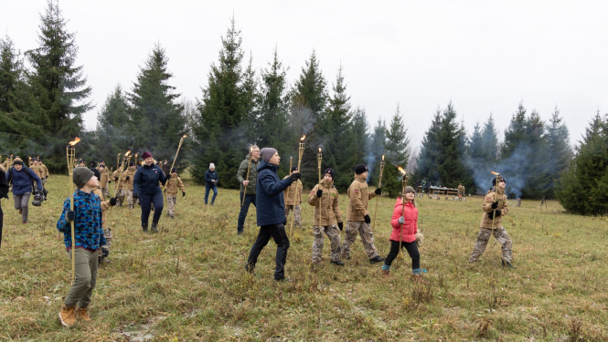 Cilvēki staigā pa meže starp eglēm
