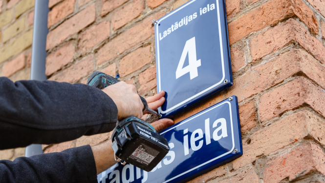 Lastādijas ielas nosaukuma zīmi piestiprina pie sienas