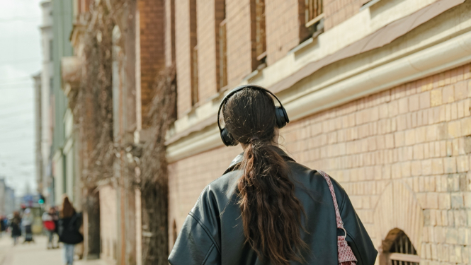 Meitene klausas mūziku austiņas