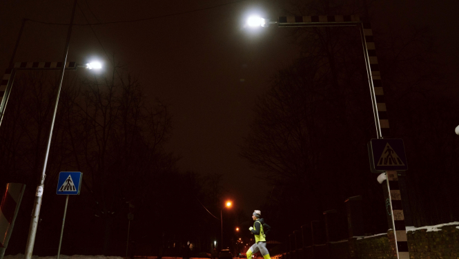 Sportists skrien pār ar LED gaismekļiem izgaismotu gajēju pāreju