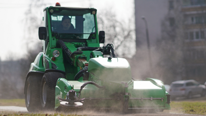 Traktors savāc smiltis no ielas