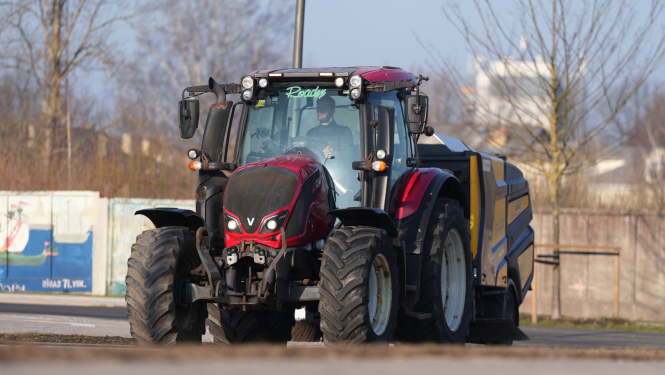Traktors savāc smiltis no ielas