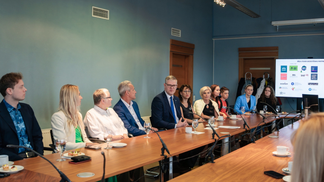 Cilvēki sēž pie galda un skatās prezentāciju