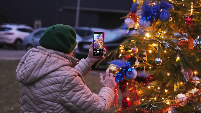 Sieviete fotografē Ziemassvētku egli