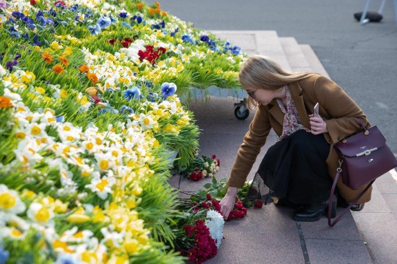 Sieviete noliek ziedus pie Brīvības pieminekļa