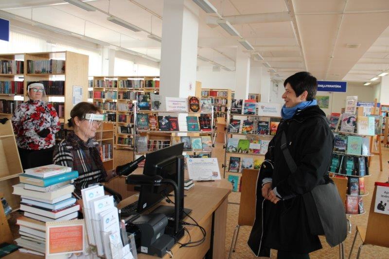 Bibliotēkas darbiniece apkalpo bibliotēkas apmeklētāju