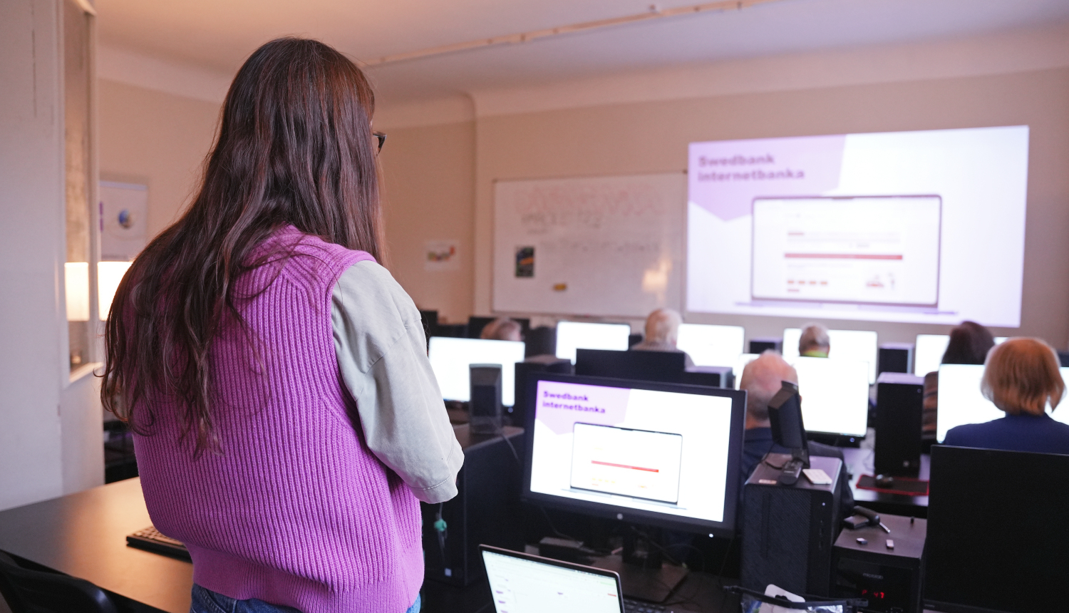 Cilvēki sēž pie datoriem un mācās