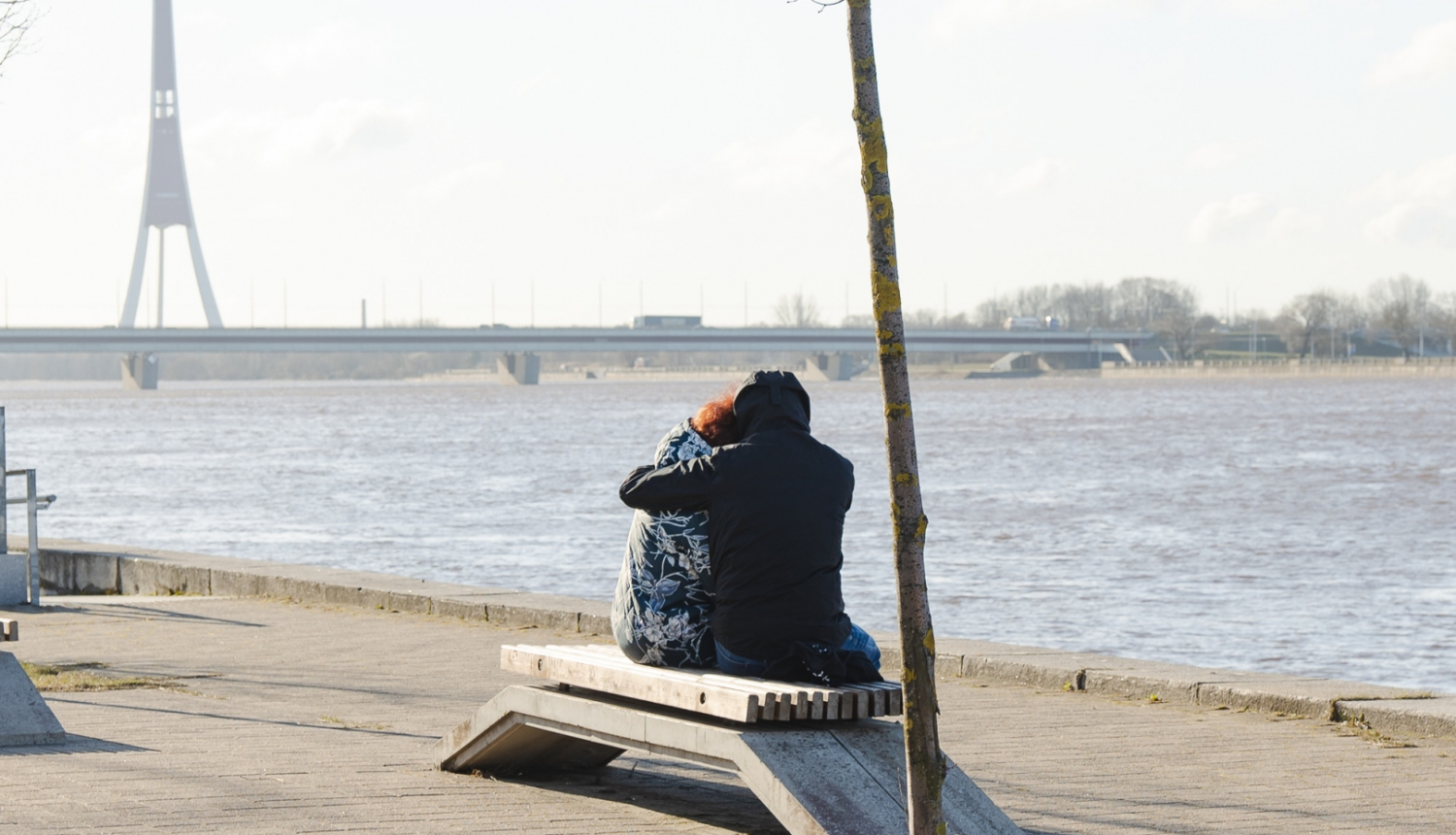 Cilvēki apķērušies sēž uz soliņa