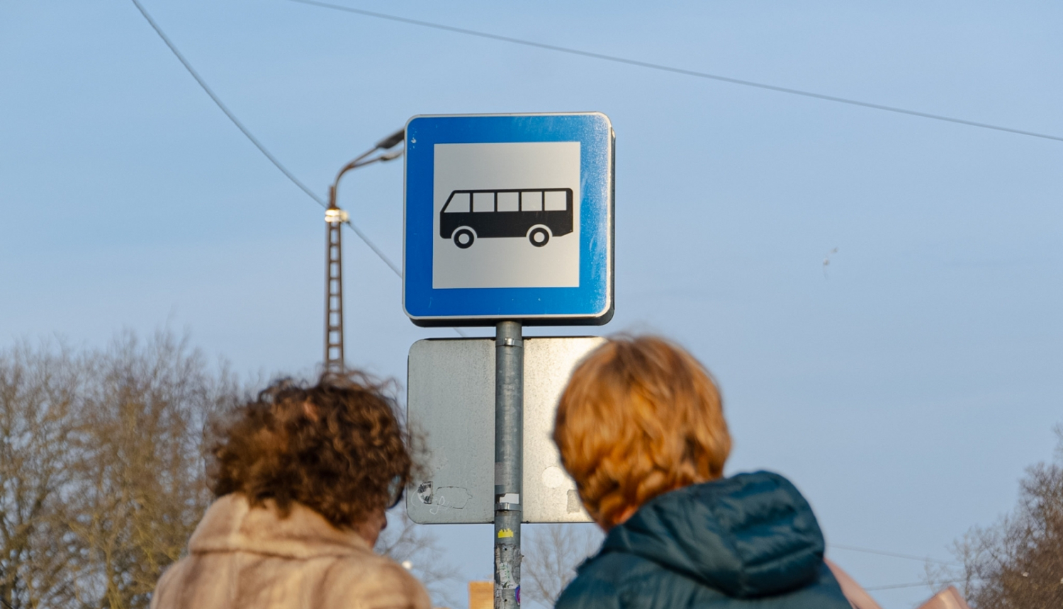 Cilvēki sabiedriskā transporta pieturā
