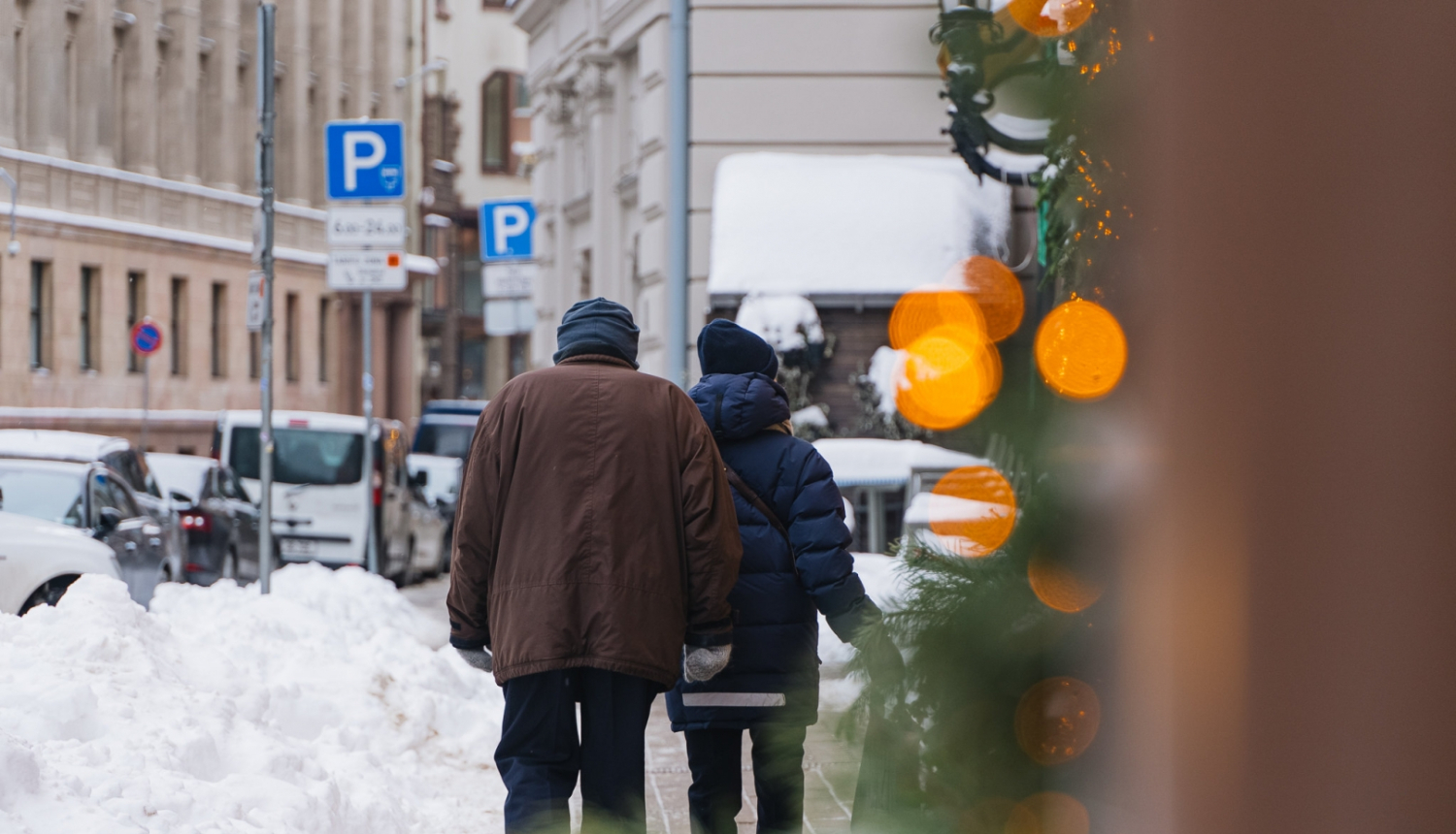 Cilvēki iet pa sniegotu ielu