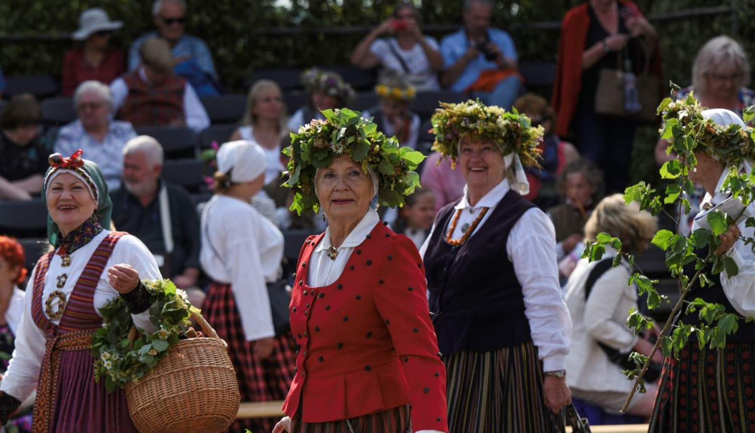 Sievietes ģērbtas tautas tērpos un ziedu vainagi galvā