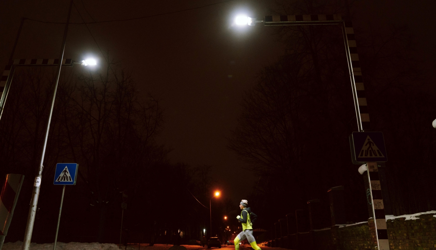 Sportists skrien pār ar LED gaismekļiem izgaismotu gajēju pāreju
