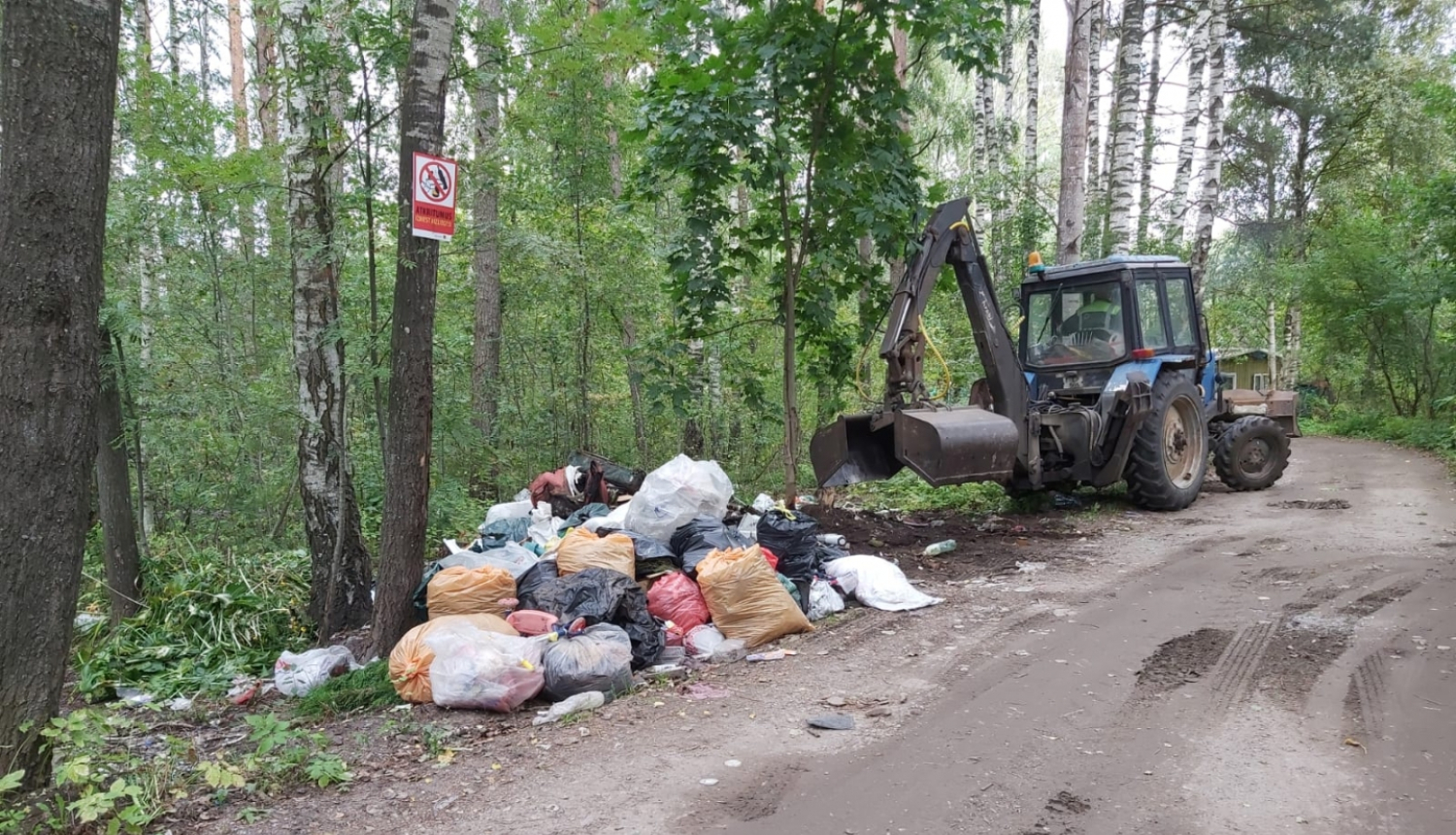 Traktors savāc atkritumu maisus