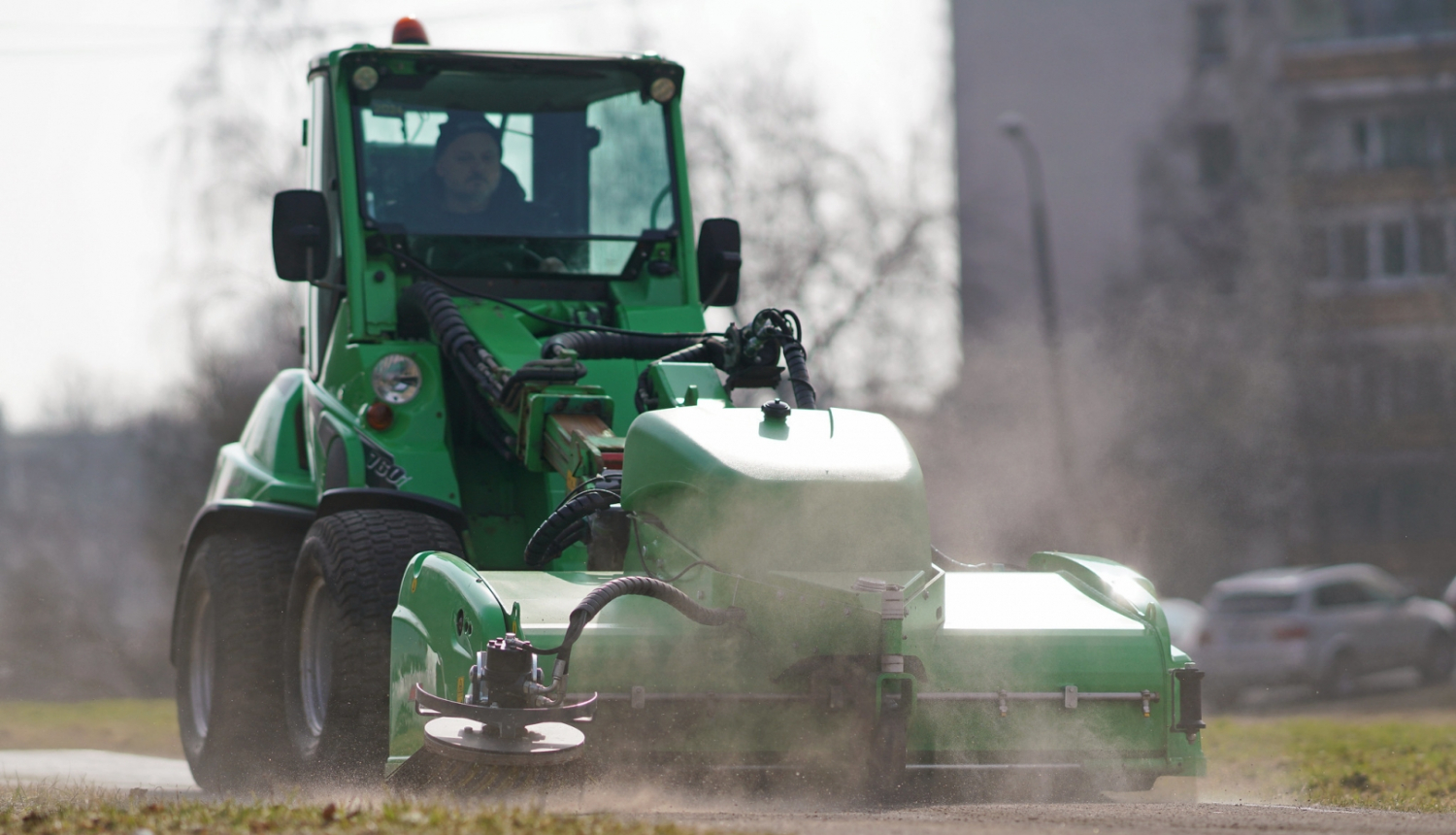 Traktors savāc smiltis no ielas