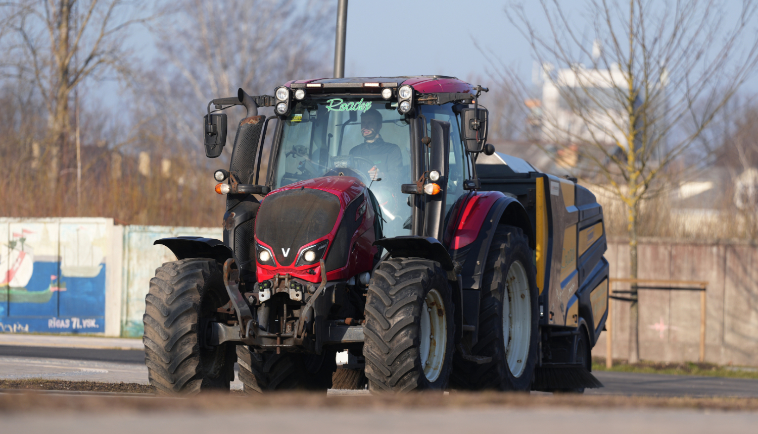 Traktors savāc smiltis no ielas