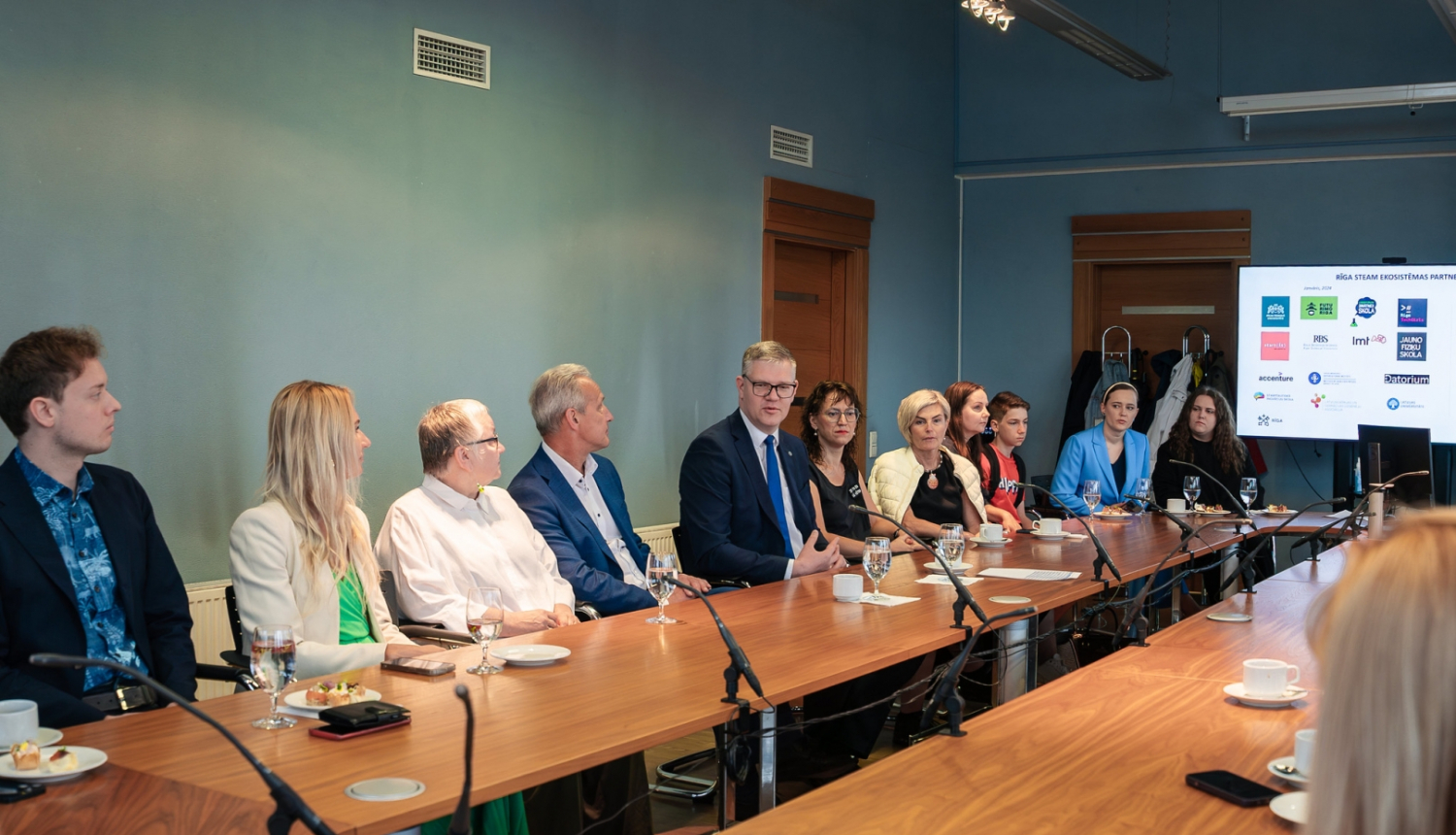 Cilvēki sēž pie galda un skatās prezentāciju